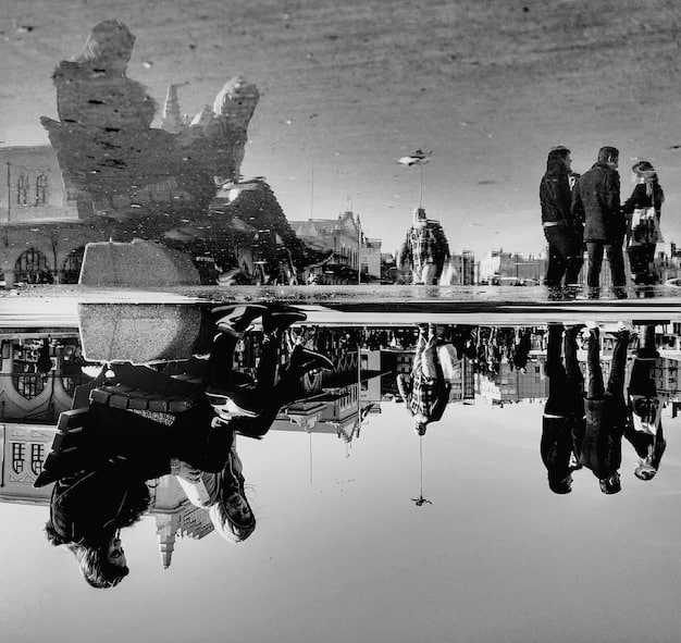 A split-screen image. On one side, a black and white photo from the Vietnam War era depicting soldiers telling jokes around a jeep with a serious tone. On the other side, a screen capture of a viral military meme from 2024.