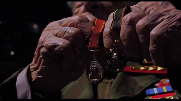 A close-up shot of a soldier receiving a medal during a formal military ceremony, focused on the detail of the medal and the expressions of pride and respect.