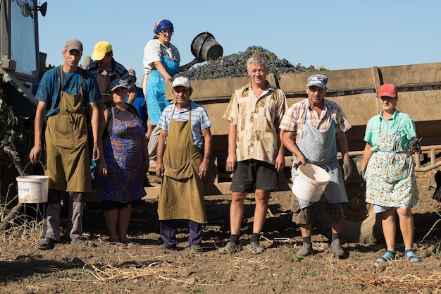 A solemn, diverse group of international aid workers distributing supplies in a rural, underdeveloped region, symbolizing humanitarian efforts and the fragility of stability without support.
