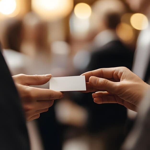 A close-up shot of a conference attendee exchanging business cards with another person, emphasizing the networking aspect of US Defense Industry Conferences: 5 Must-Attend Events for Networking and Business Development. The focus is on the interaction and connection between professionals.