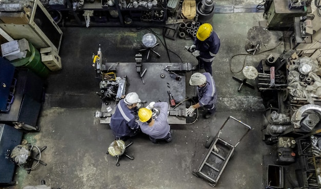 A detailed overhead shot of a manufacturing floor with various machinery and skilled technicians working on precision components, representing the critical role of SMBs in the defense supply chain.